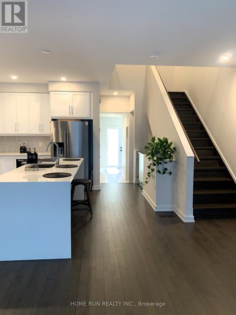 A modern kitchen with a stainless steel refrigerator and a wooden floor.