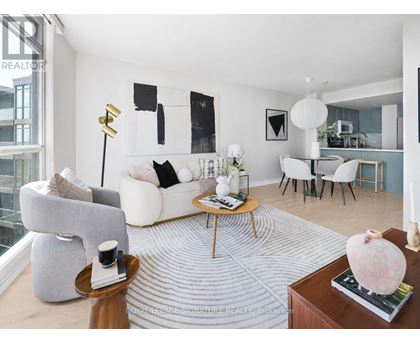A living room with a grey couch, a coffee table, and a large abstract painting on the wall.