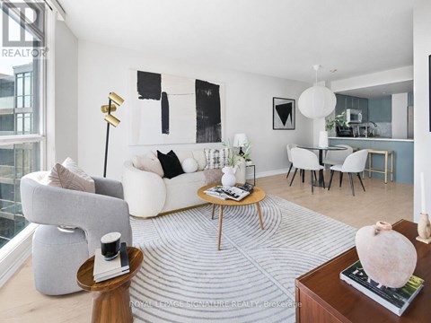 A living room with a grey couch, a coffee table, and a large abstract painting on the wall.