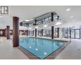 A large indoor swimming pool with a glass ceiling and a tiled floor.