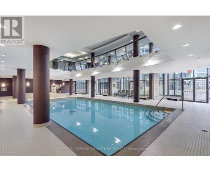 A large indoor swimming pool with a glass ceiling and a tiled floor.