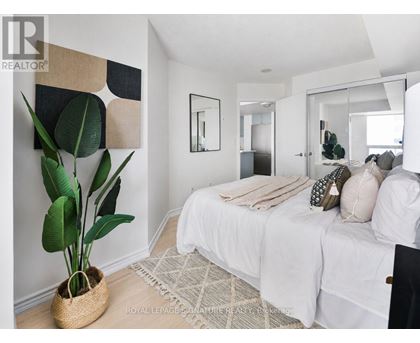 A bedroom with a large bed and a plant in a woven basket.