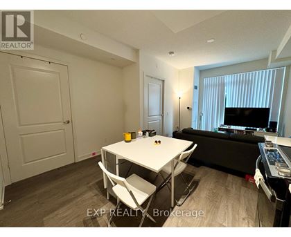 A living room with a white table and chairs, a black couch, and a television.