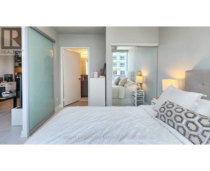 A bedroom with a large bed and a glass door leading to a balcony.
