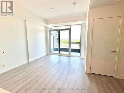 A spacious room with a sliding glass door leading to a balcony.