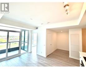 A spacious room with a sliding glass door leading to a balcony.