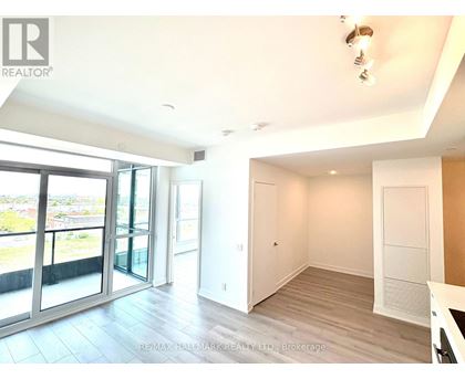 A spacious room with a sliding glass door leading to a balcony.