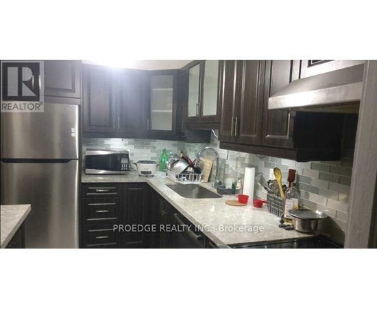 A kitchen with a refrigerator and a sink.