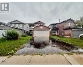 A wet driveway leads to a garage in front of a house.