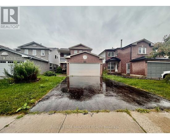 A wet driveway leads to a garage in front of a house.