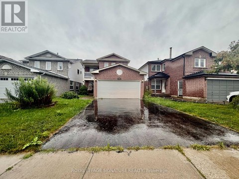 A wet driveway leads to a garage in front of a house.
