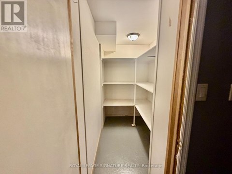 A white hallway with shelves and a light on the ceiling.