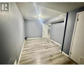 A room with wooden flooring and white walls, with a door on the right side.
