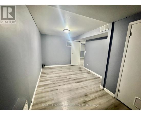 A room with wooden flooring and white walls, with a door on the right side.