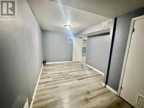 A room with wooden flooring and white walls, with a door on the right side.