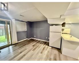 A spacious room with a slanted ceiling and a kitchenette.