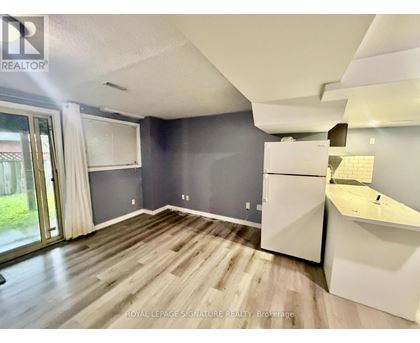 A spacious room with a slanted ceiling and a kitchenette.