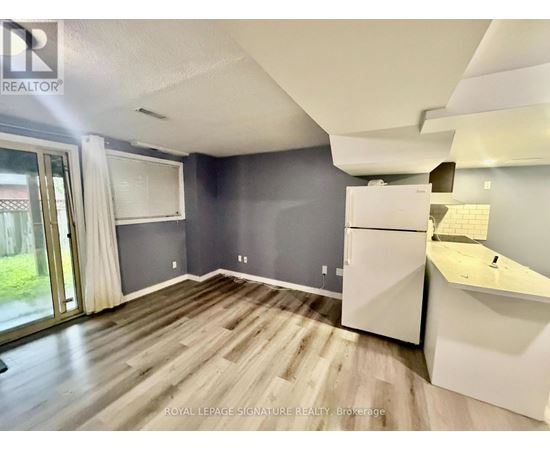 A spacious room with a slanted ceiling and a kitchenette.