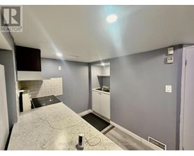 A room with a grey floor and a white wall with a black television mounted on it.