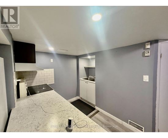 A room with a grey floor and a white wall with a black television mounted on it.