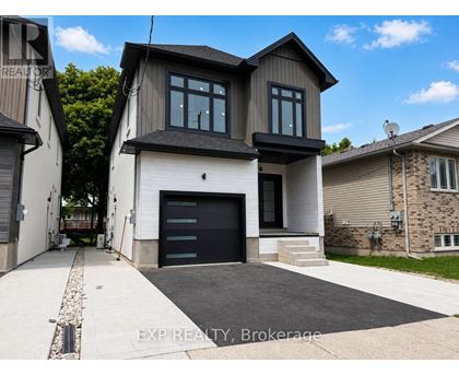 A modern house with a black garage door is for sale.