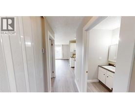 A hallway with a white door on the left and a bathroom on the right.