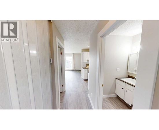 A hallway with a white door on the left and a bathroom on the right.