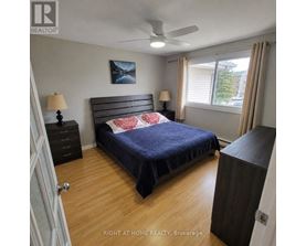 A bedroom with a bed, nightstand, and a ceiling fan.