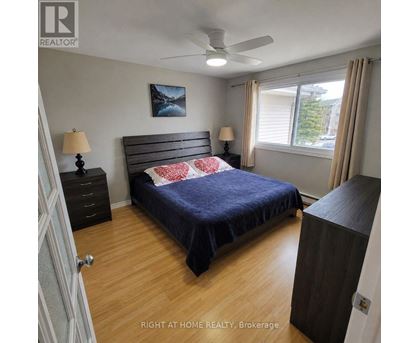 A bedroom with a bed, nightstand, and a ceiling fan.