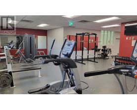 A gym with a variety of equipment including a stationary bike, a rowing machine, and a weight bench.