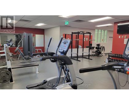 A gym with a variety of equipment including a stationary bike, a rowing machine, and a weight bench.