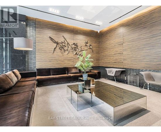 A modern living room with a glass coffee table and a brown leather couch.