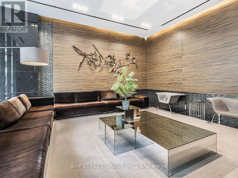 A modern living room with a glass coffee table and a brown leather couch.