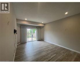 A spacious room with wooden flooring and a sliding glass door leading to a balcony.