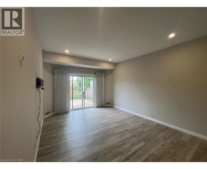 A spacious room with wooden flooring and a sliding glass door leading to a balcony.