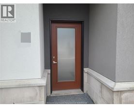 A brown door with a glass panel is set in a white wall.