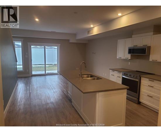 A kitchen with white cabinets and a wooden floor.