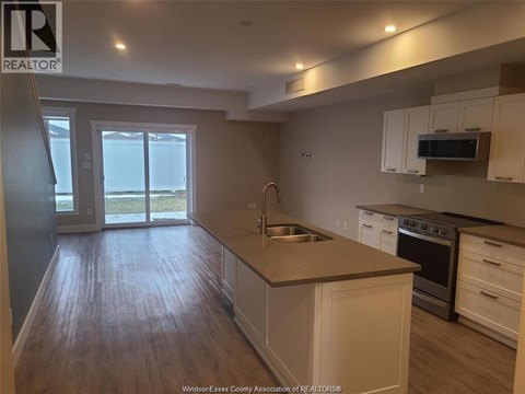 A kitchen with white cabinets and a wooden floor.
