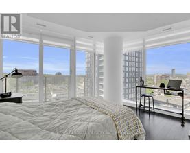 A bedroom with a large bed and a desk with a laptop on it.