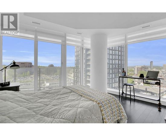 A bedroom with a large bed and a desk with a laptop on it.