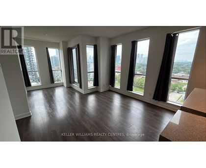 A living room with a couch and a table in front of a window with a city view.