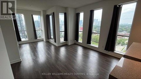 A living room with a couch and a table in front of a window with a city view.