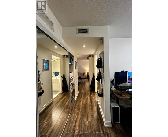 A hallway with wood floors and a white ceiling.