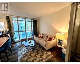 A living room with a couch, coffee table, and a window with a view of a building.