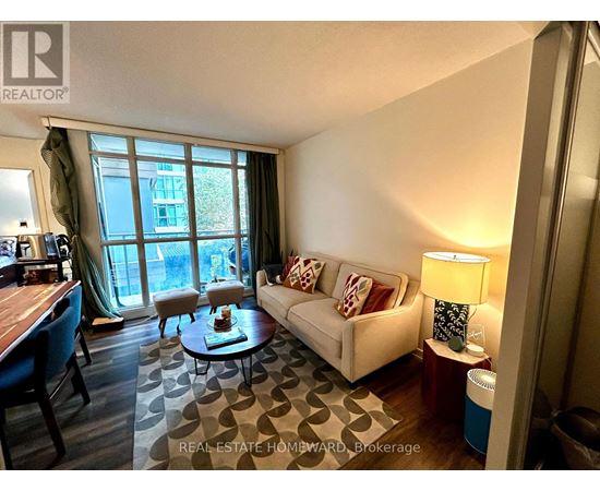A living room with a couch, coffee table, and a window with a view of a building.