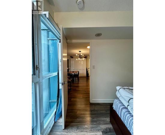 A bedroom with a bed and a dining area in the background.