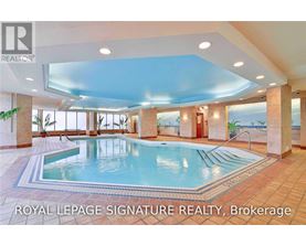 A large indoor swimming pool with a tiled floor and a glass ceiling.