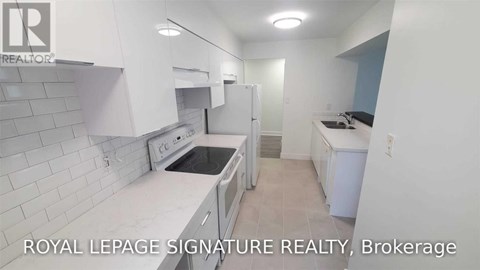 A white kitchen with a refrigerator, oven, and sink.