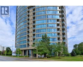 A tall building with many windows is surrounded by trees and grass.