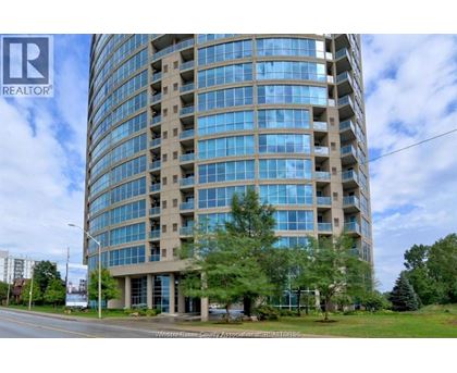 A tall building with many windows is surrounded by trees and grass.